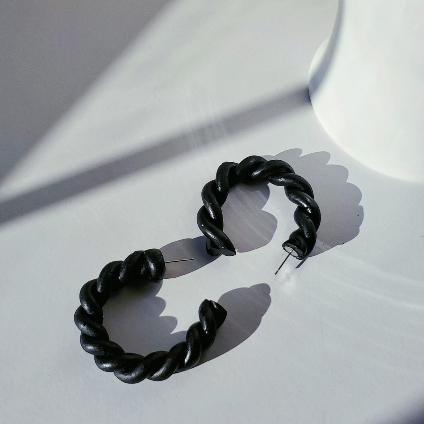 Stylish black polymer clay twisted hoop earrings, perfect for adding a modern touch to any outfit.