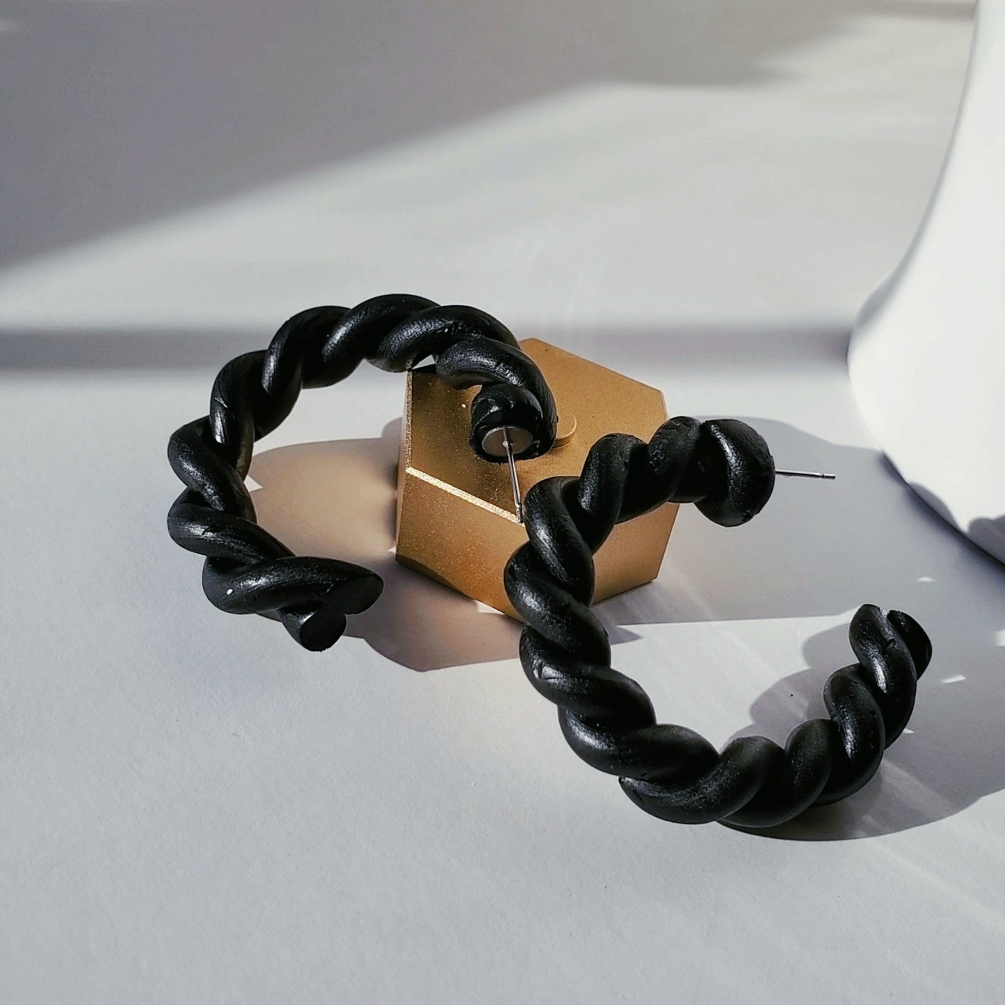 Stylish black polymer clay twisted hoop earrings, perfect for adding a modern touch to any outfit.