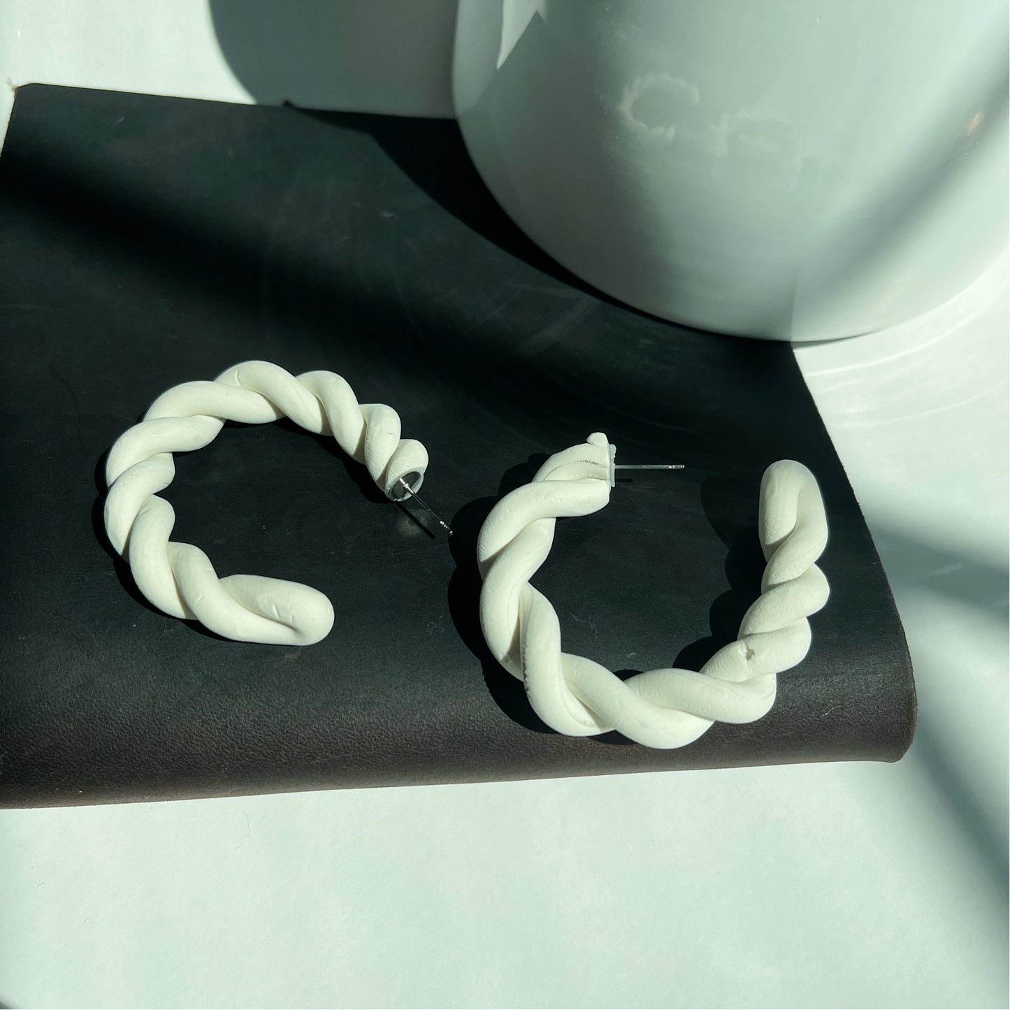 Stylish white polymer clay twisted hoop earrings, perfect for adding a modern touch to any outfit.
