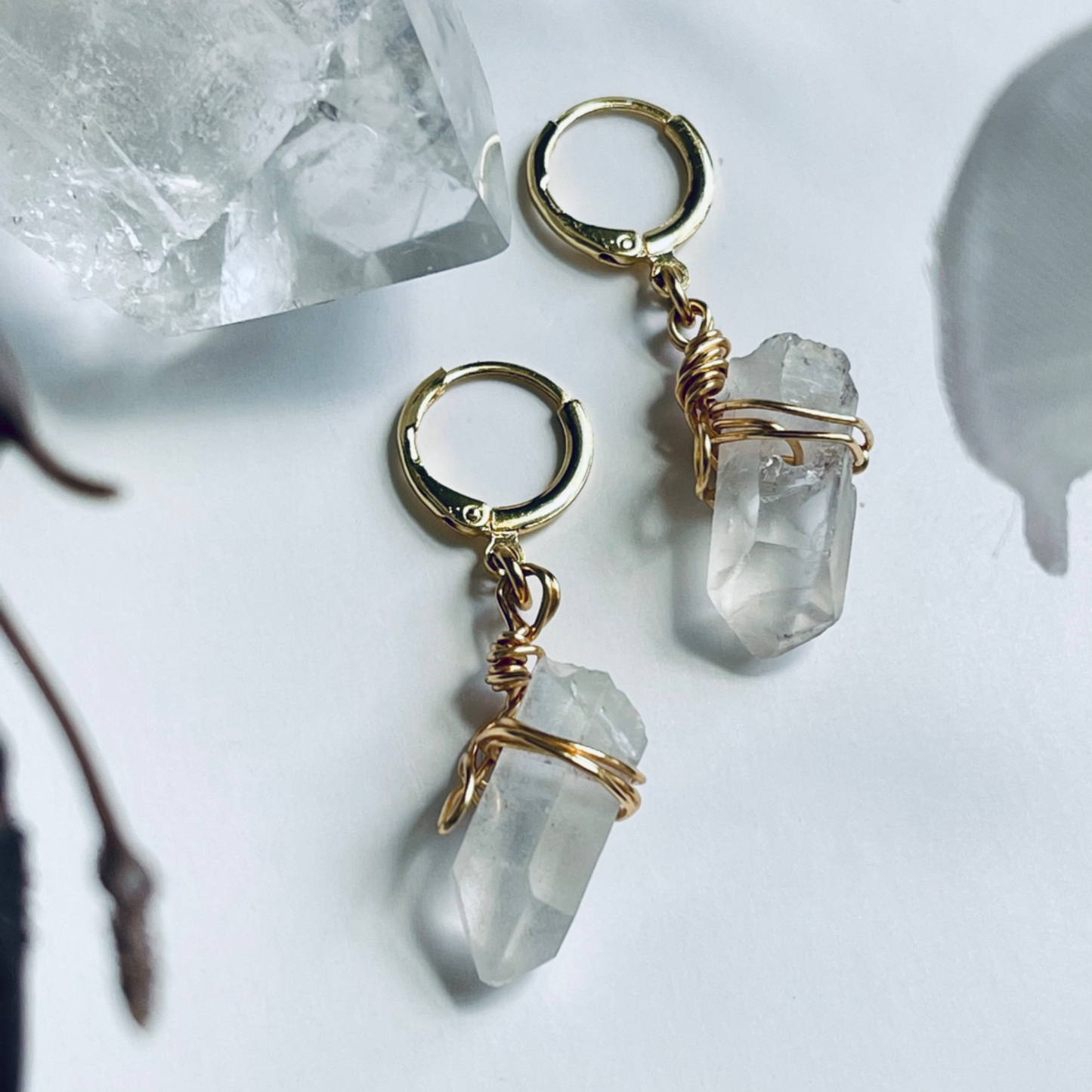 Handcrafted Mini Quartz Hoop Earring featuring a clear quartz gemstone delicately wrapped in 18k gold-plated wire, attached to a lightweight mini hoop. Perfect for layering or wearing alone, this unique piece embodies the properties of clarity and healing.